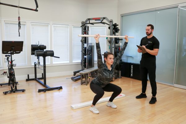 personal trainer helping female lift