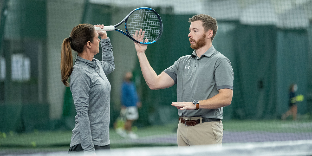 client receiving tips on how to hold her racket